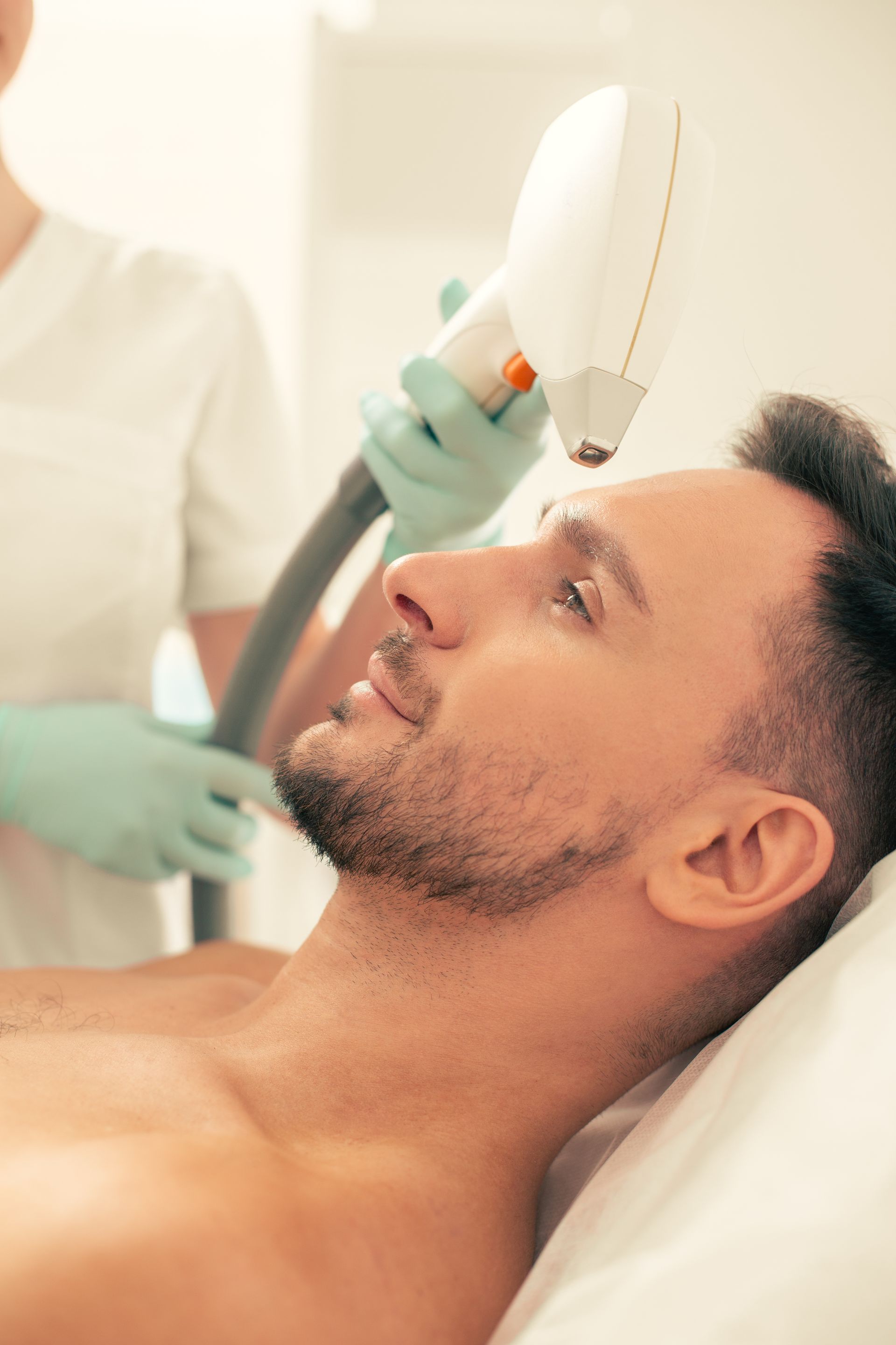 a man is getting a laser hair removal treatment on his face .