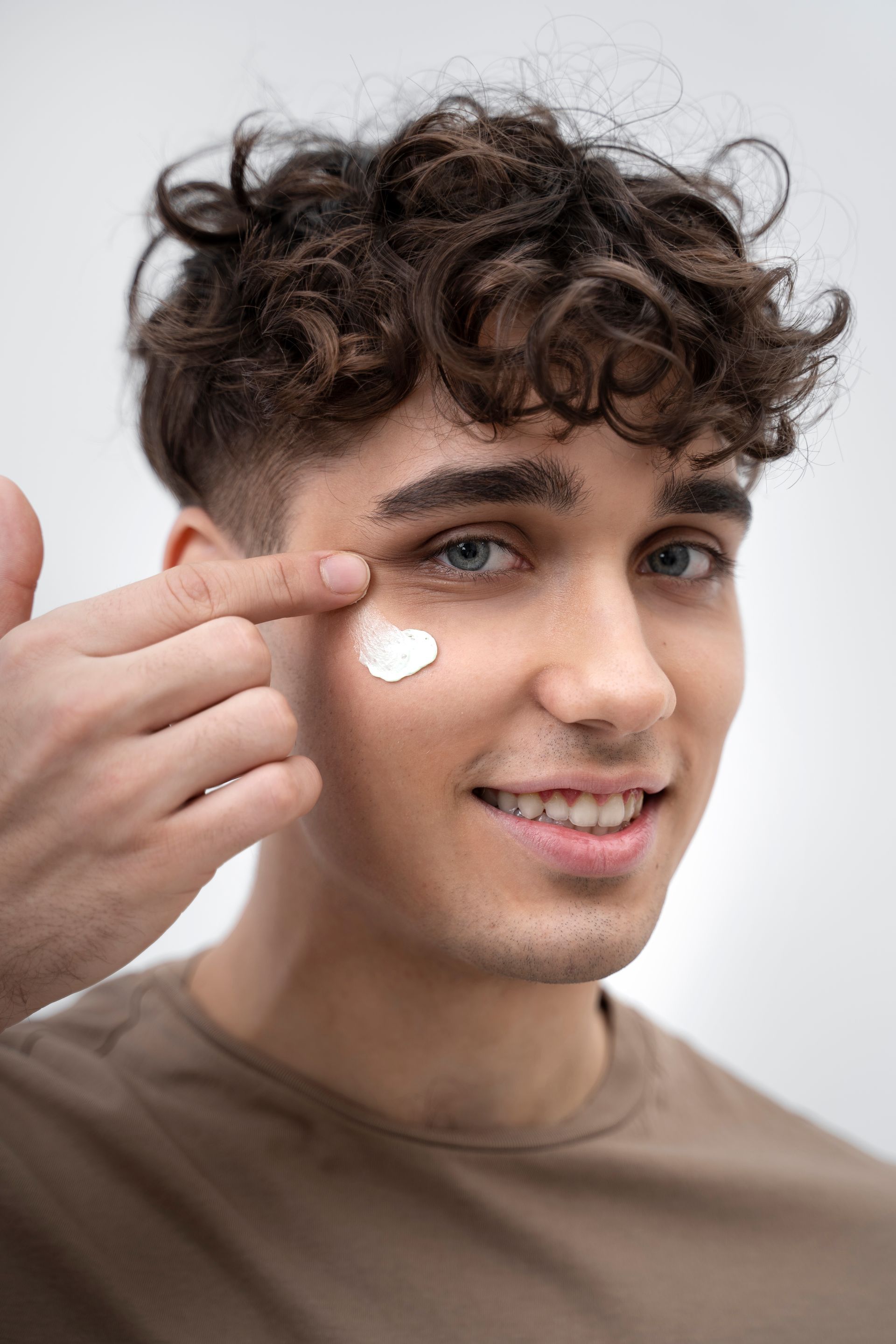 a young man is applying cream to his face .
