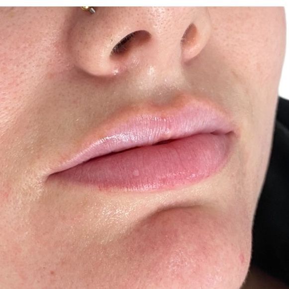 A close up of a woman 's lips with a nose ring.