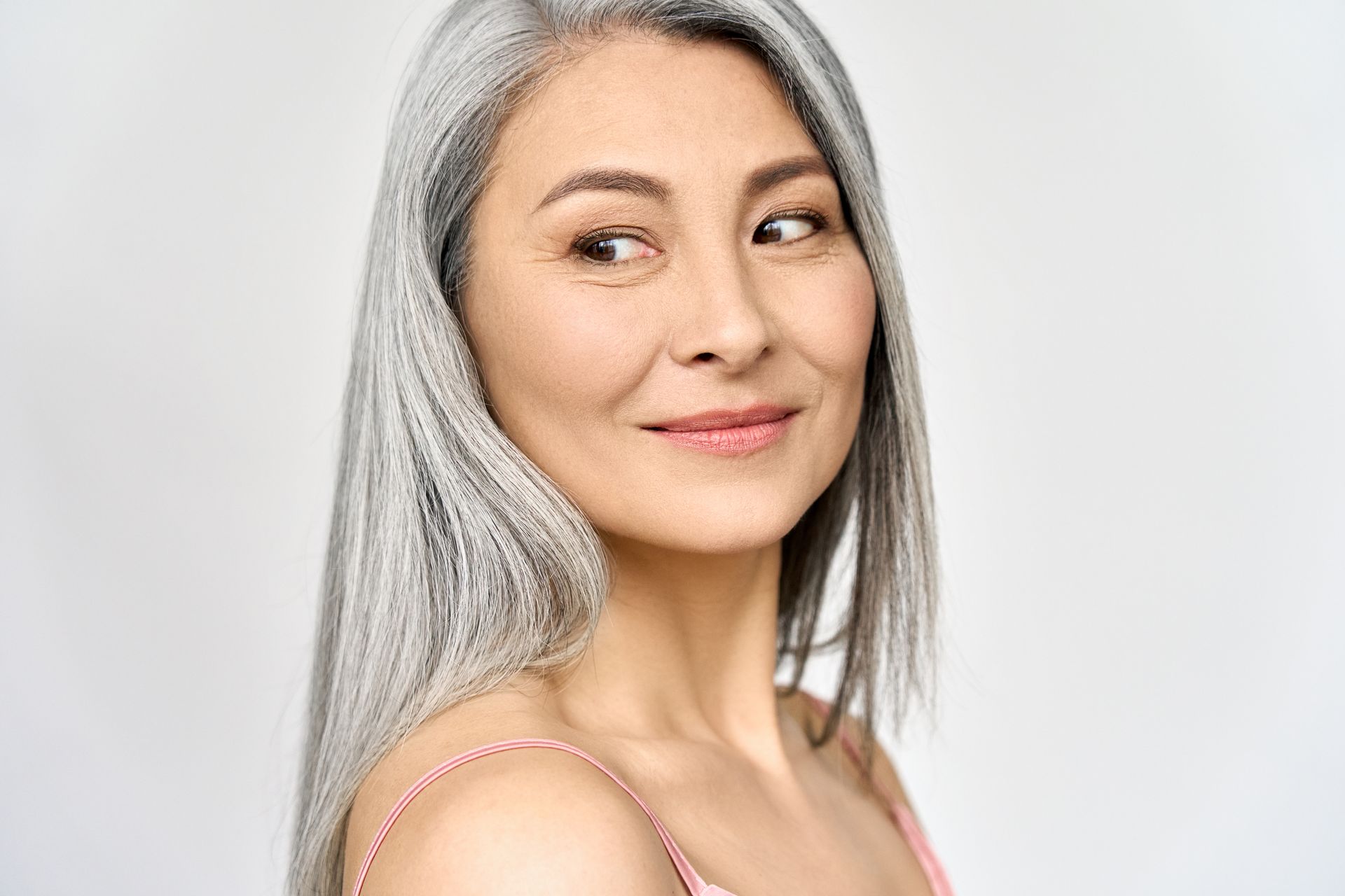 A woman with gray hair is smiling and looking at the camera.