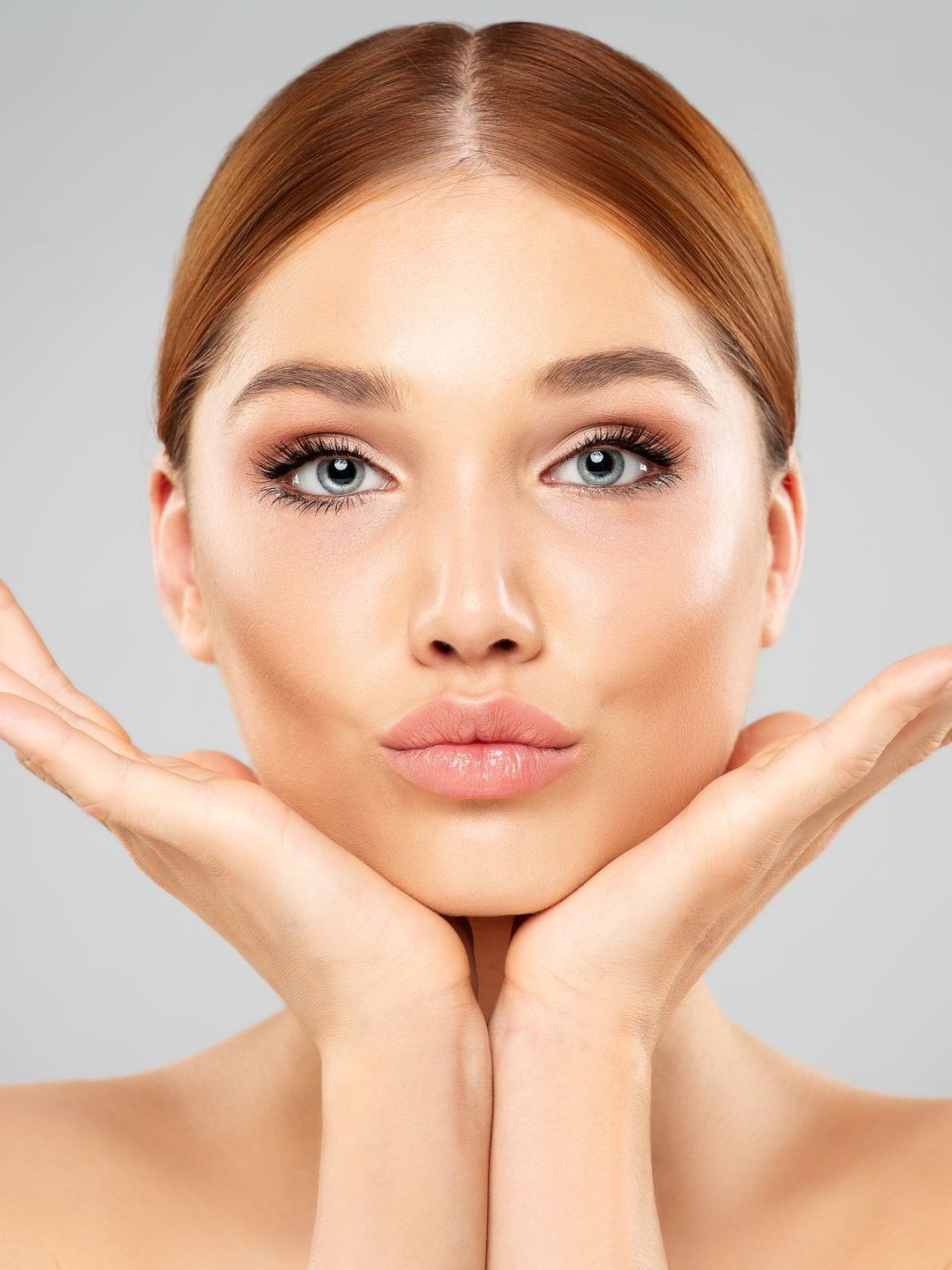 A close up of a woman 's face with her hands on her chin.