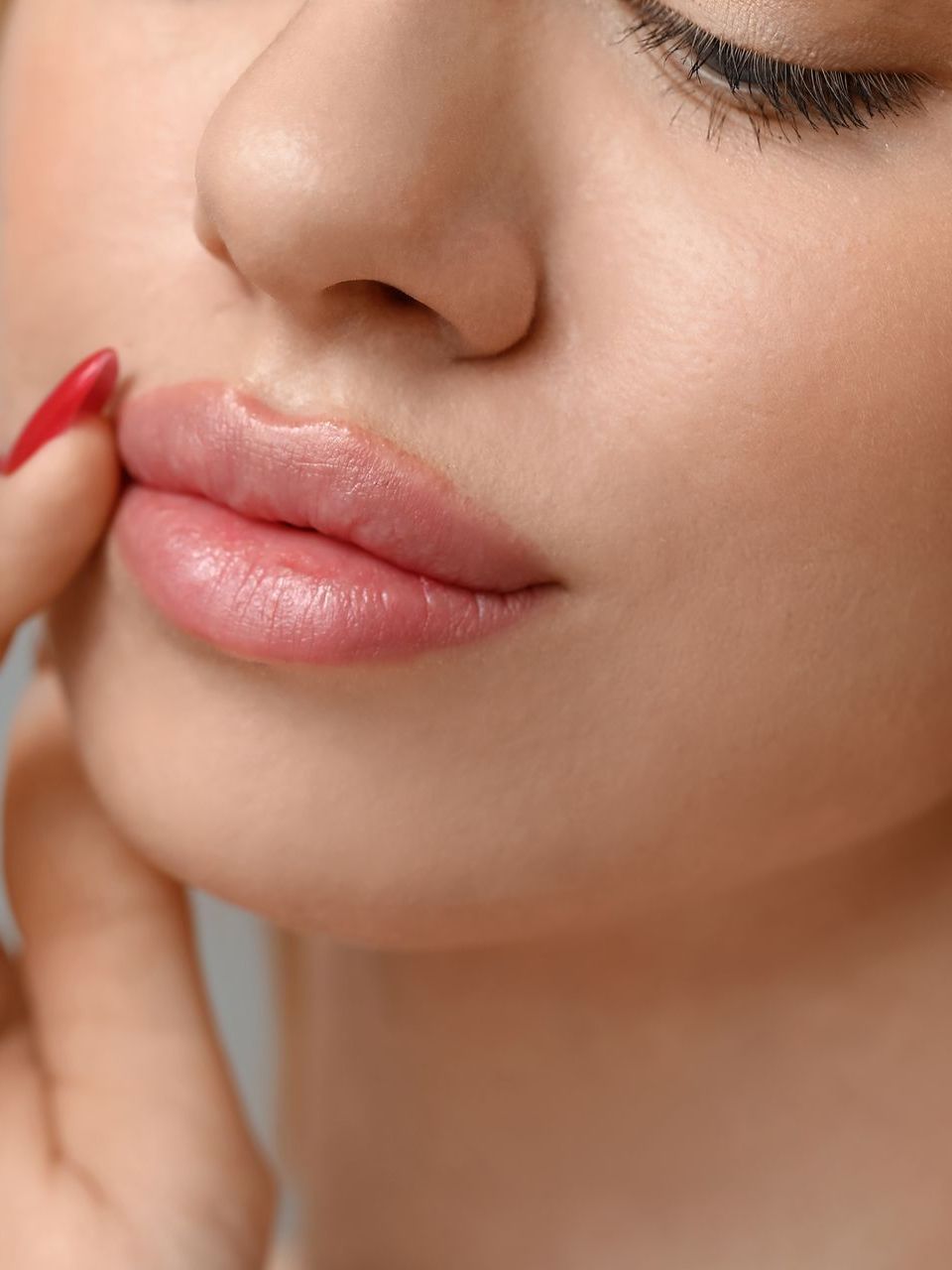 A close up of a woman 's face with red nails.