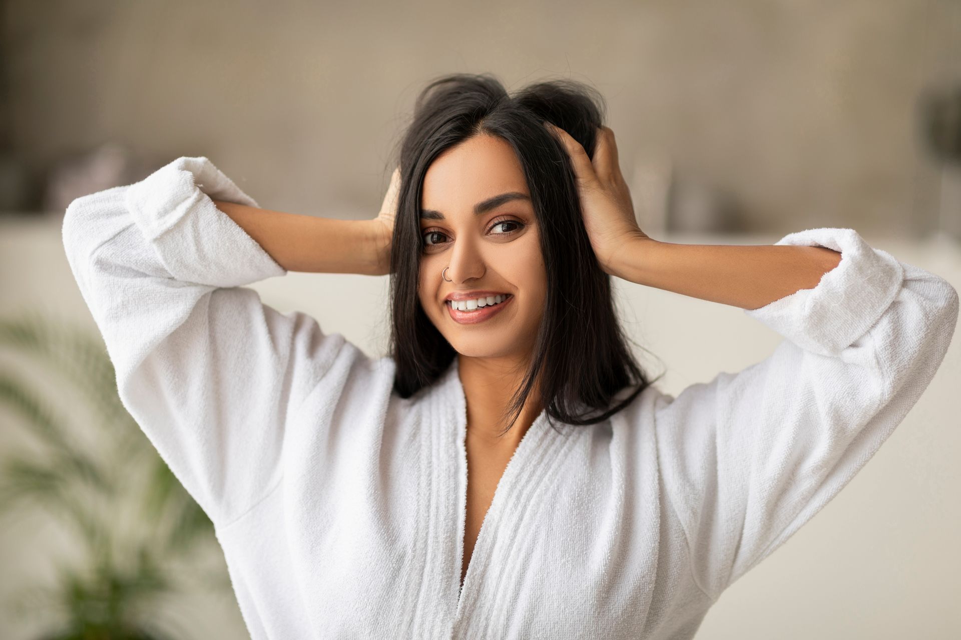 a woman in a white robe is smiling and holding her hair .