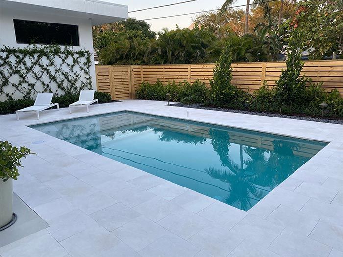 There is a large swimming pool in the backyard of a house.