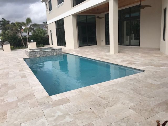 A large swimming pool is in the backyard of a house.