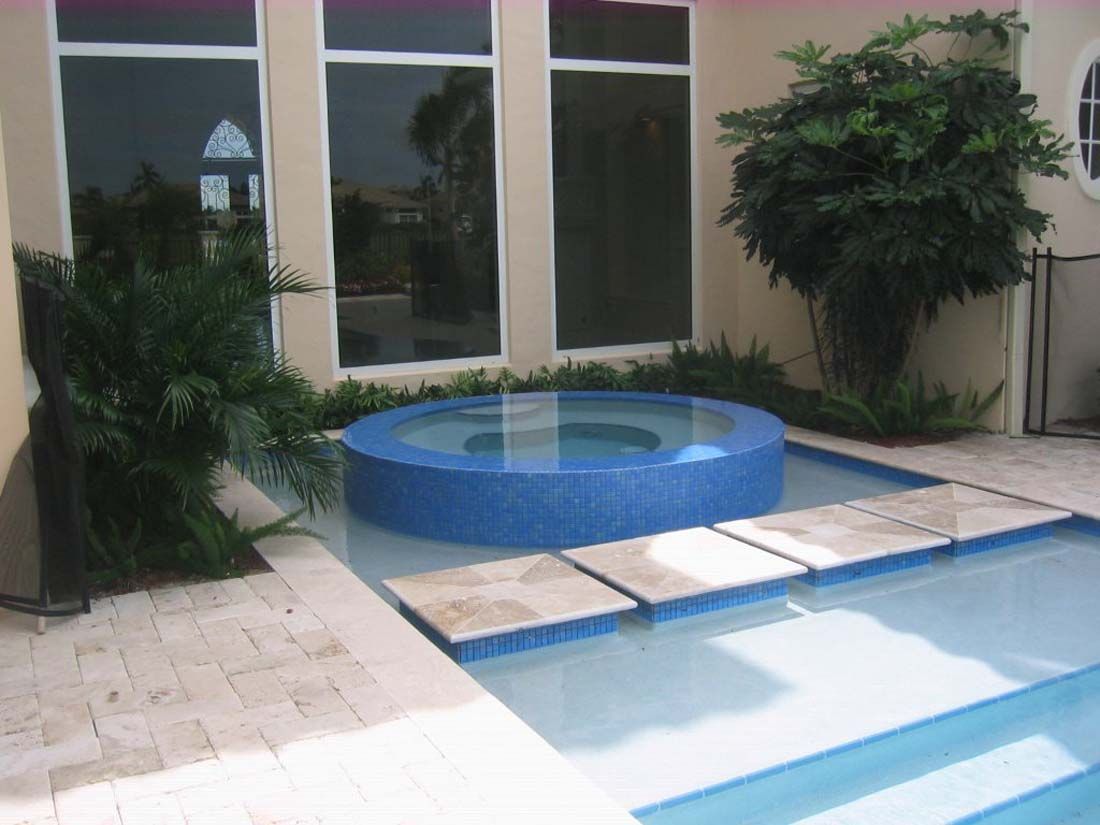 A swimming pool with a blue jacuzzi in the middle