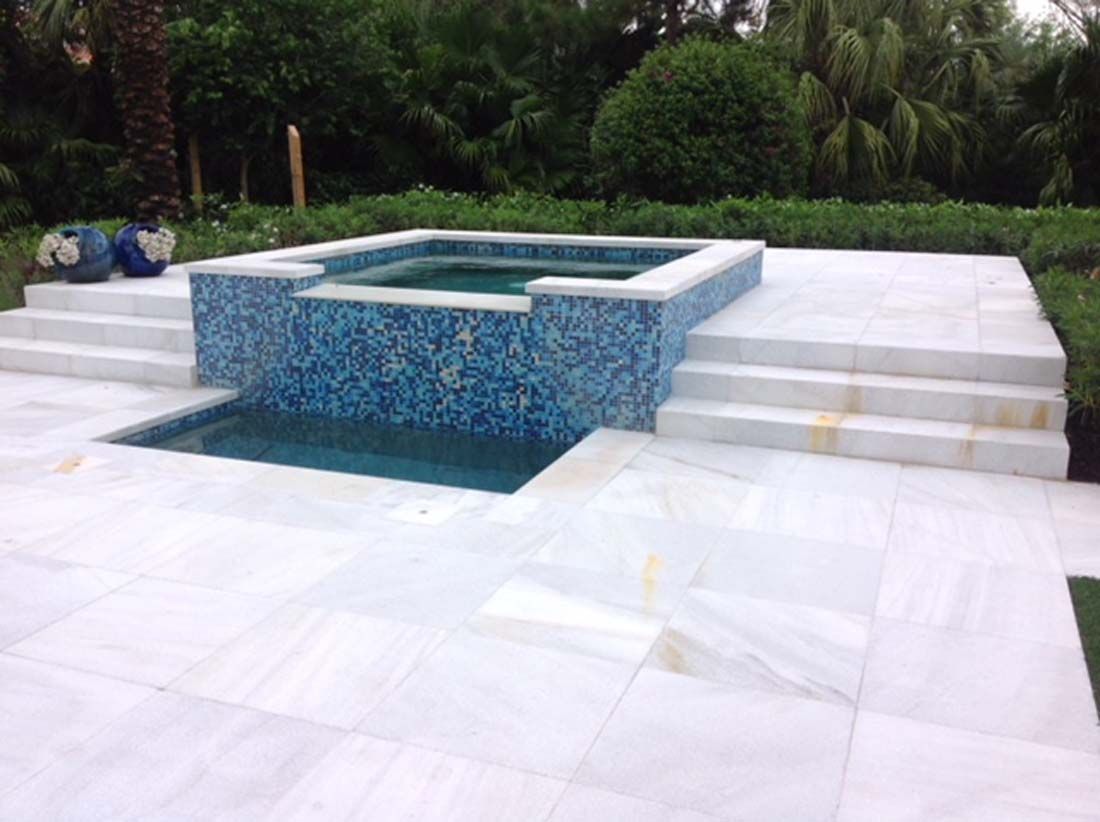 A swimming pool with a hot tub in the middle of it.