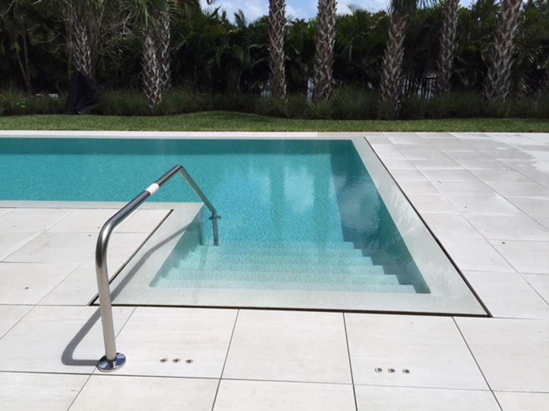 A swimming pool with stairs leading to it and palm trees in the background