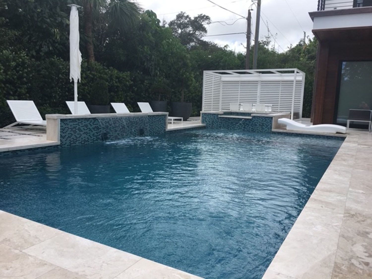 A large swimming pool surrounded by chairs and umbrellas