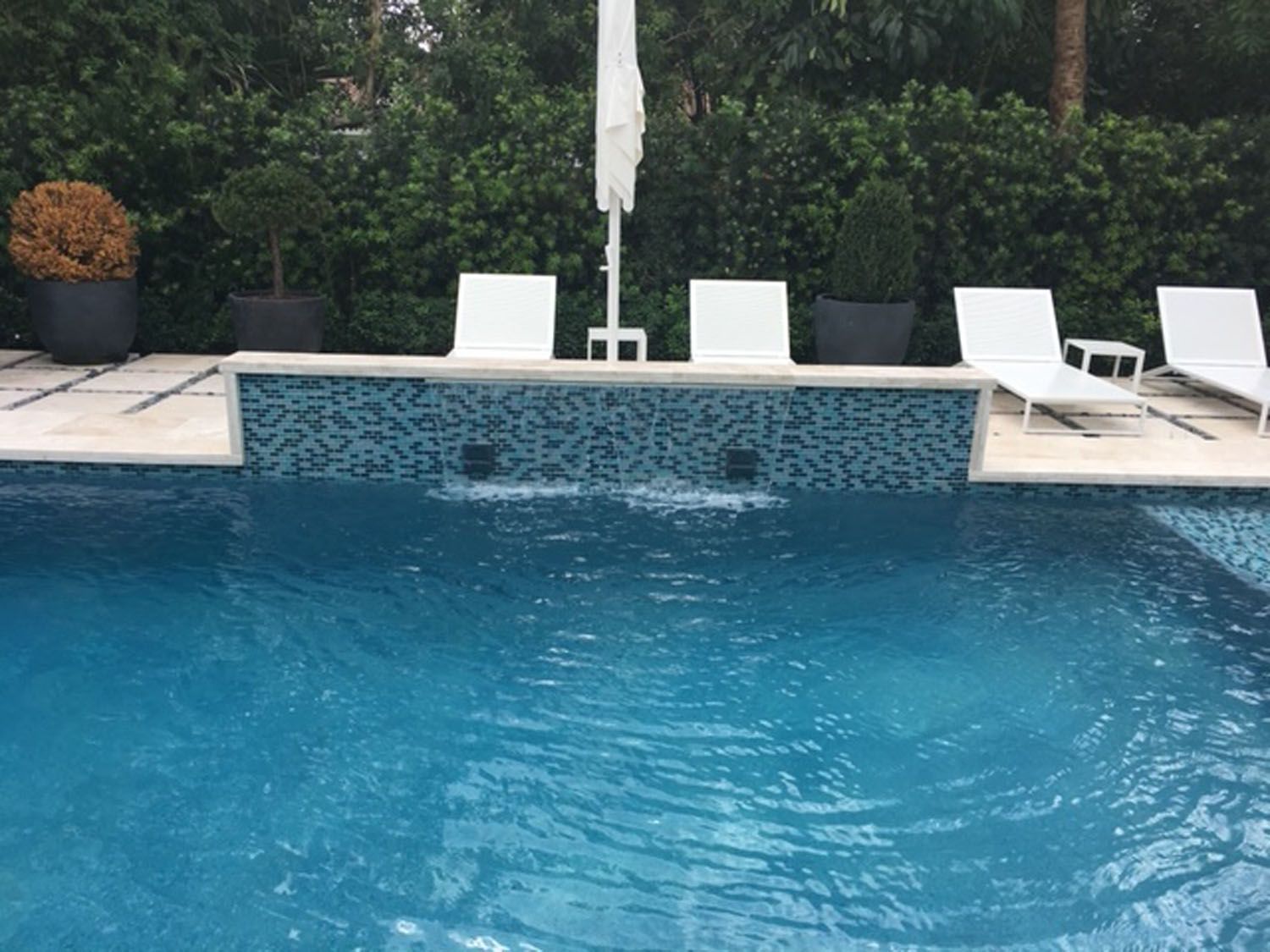 A large swimming pool surrounded by chairs and umbrellas.