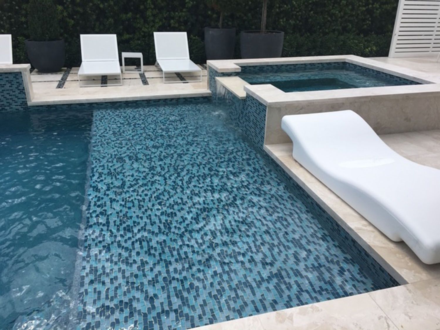 A large swimming pool with chairs and a hot tub