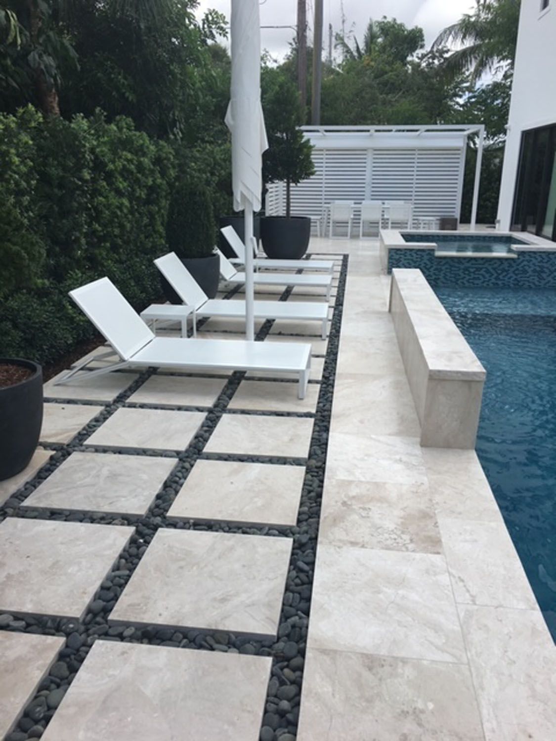 A row of white lounge chairs next to a swimming pool