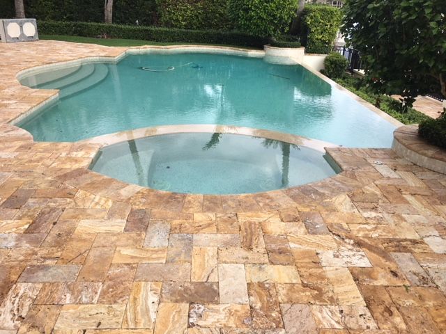 A large swimming pool is surrounded by a tiled patio.