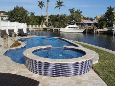 A swimming pool with a hot tub and a boat in the background