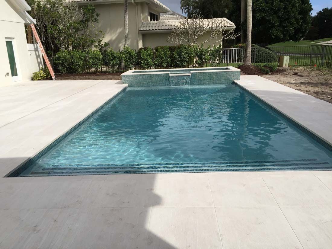 There is a large swimming pool in the backyard of a house.