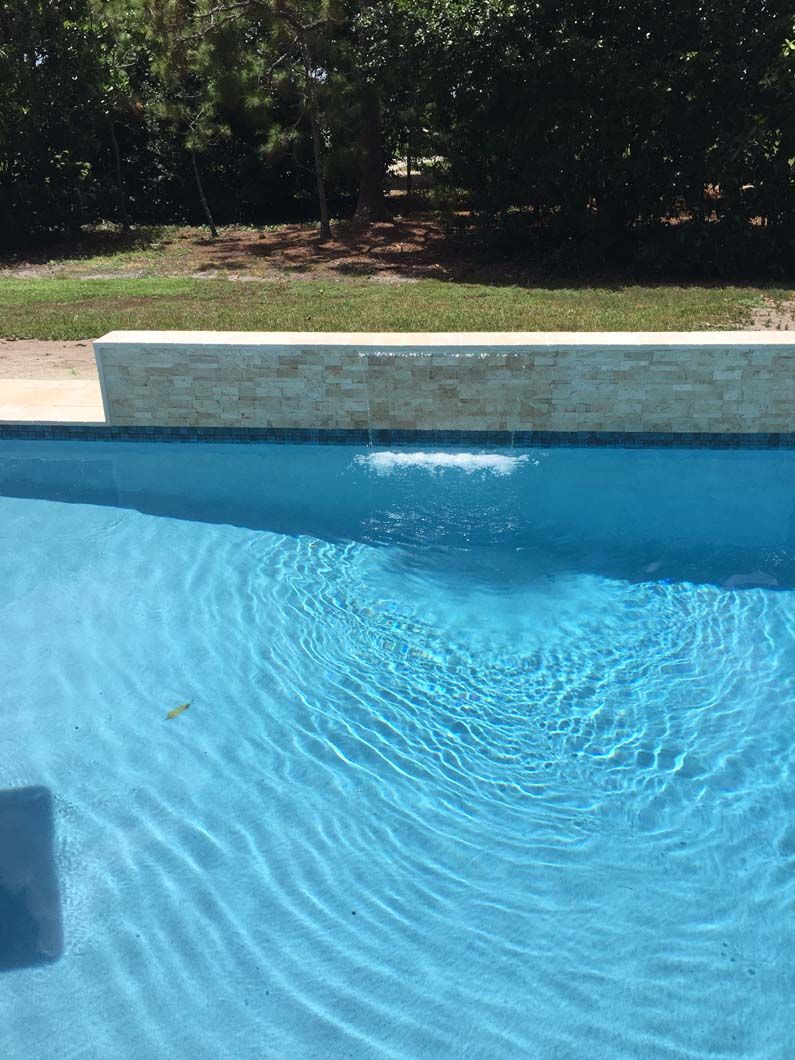 A large swimming pool filled with blue water and trees in the background.