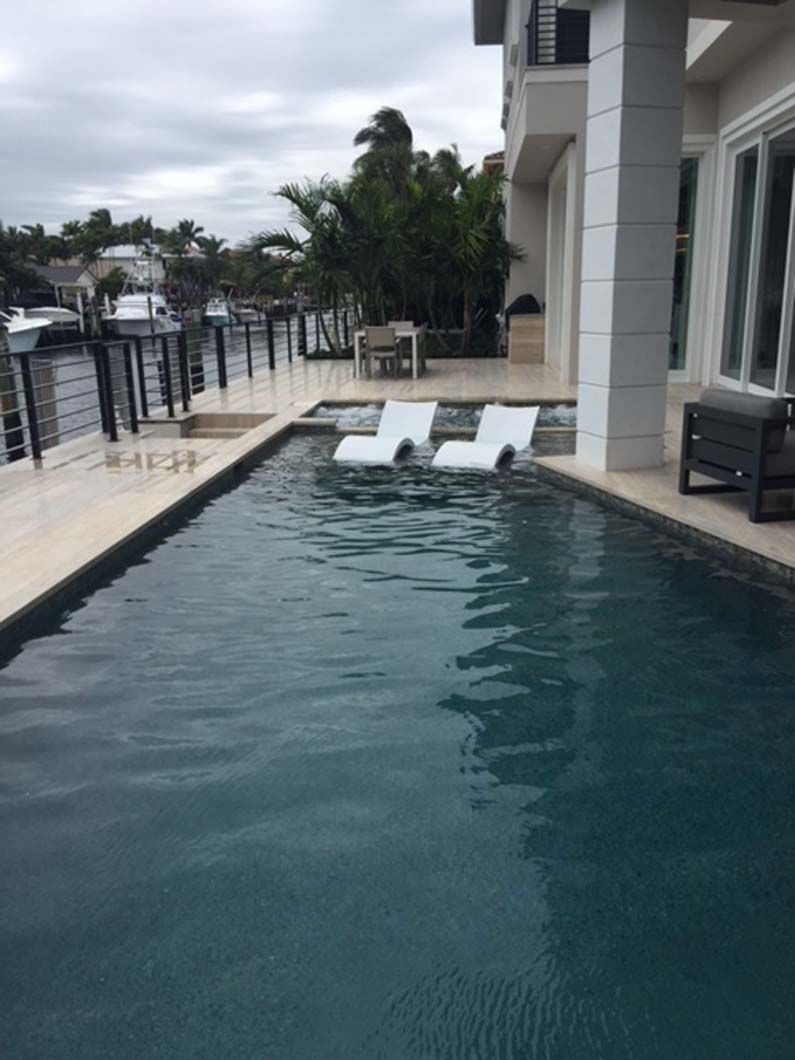 A large swimming pool with two white chairs in it