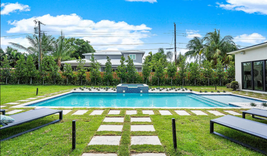 There is a large swimming pool in the backyard of a house.