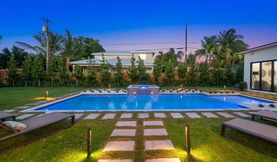There is a large swimming pool in the backyard of a house.