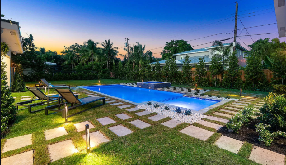 There is a large swimming pool in the backyard of a house.