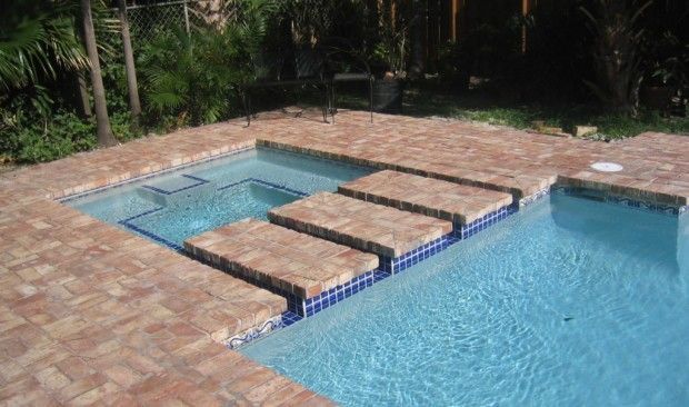 A swimming pool with steps leading to it and a brick patio.