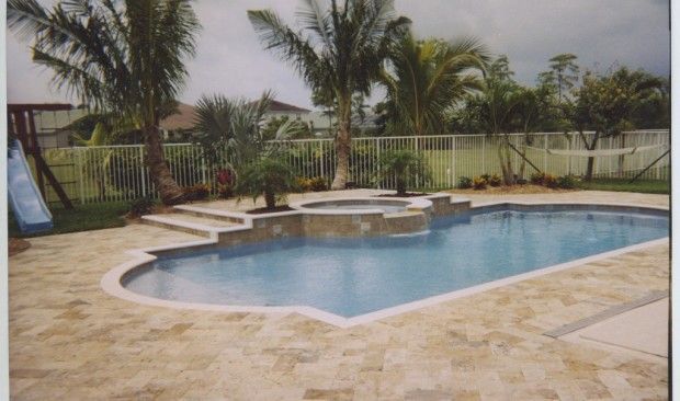 A large swimming pool surrounded by palm trees and a slide