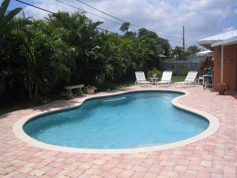 A large swimming pool is surrounded by chairs and trees