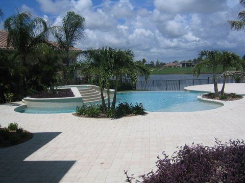 A large swimming pool surrounded by palm trees on a sunny day