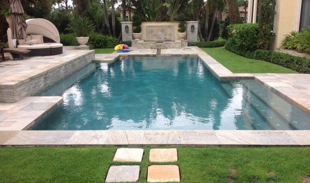 There is a large swimming pool in the backyard of a house.