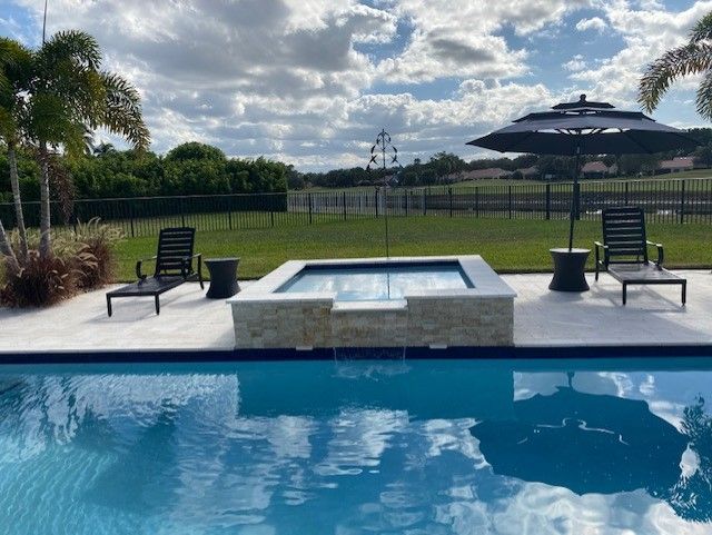 A large swimming pool with chairs and umbrellas around it.