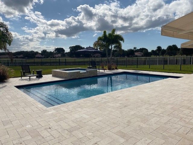 There is a large swimming pool in the backyard of a house.