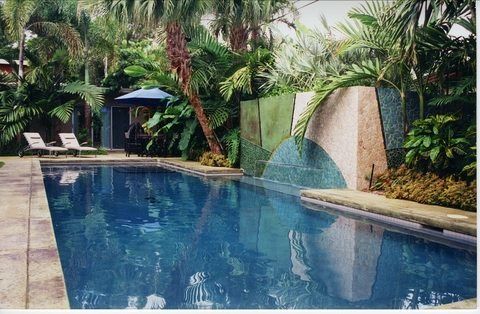 A large swimming pool surrounded by palm trees and chairs