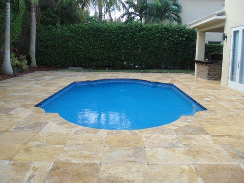 A large swimming pool is surrounded by a tiled patio.