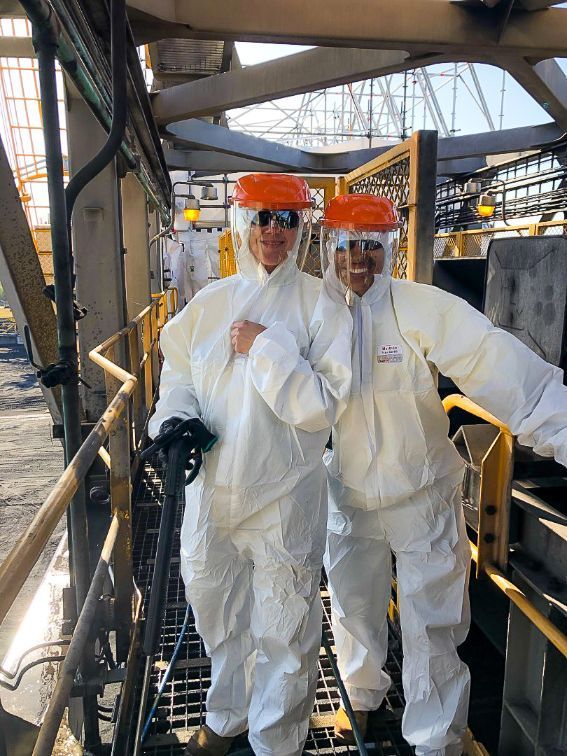 Two People in White Protective Suits and Orange Hard Hats Pose on Industrial Walkways — Tincone Pty Ltd in Paget, QLD