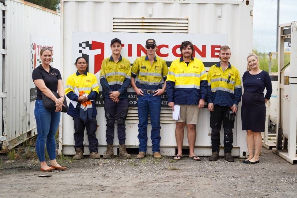 A Group of Seven People Standing in Front of a Container With the Company Logo — Tincone Pty Ltd in Paget, QLD