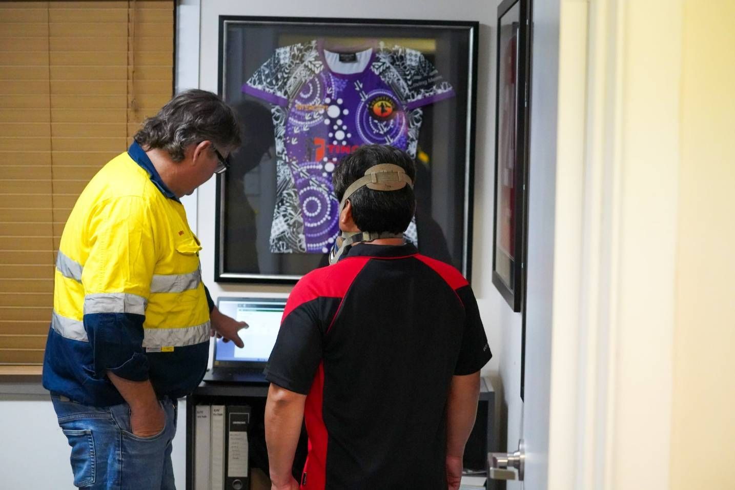 Two Men Looking at a Laptop in an Office. The Man on the Left Wears a Yellow High-visibility Vest — Tincone Pty Ltd in Paget, QLD