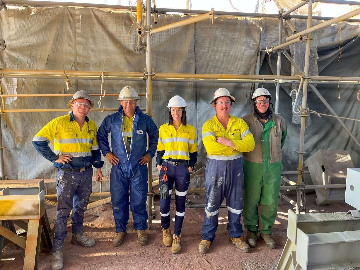 Five Workers in Safety Gear Pose in Front of Scaffolding and a Construction Site. They Wear Hard Hats, High-visibility Shirts, and Work Pants — Tincone Pty Ltd in Paget, QLD