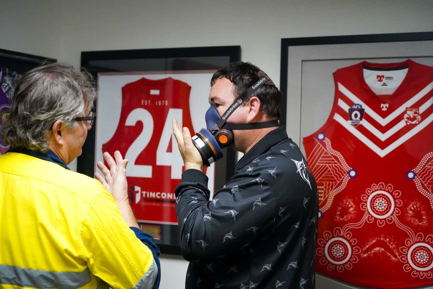 A Man Wearing a Respirator Mask Adjusts It While Talking to Another Man in a Yellow Vest — Tincone Pty Ltd in Paget, QLD
