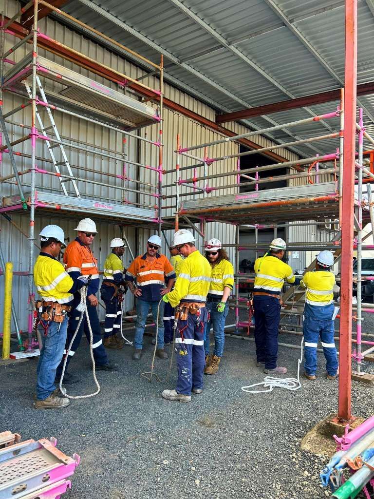 Construction Workers in Hard Hats and Safety Vests Stand Near Scaffolding Inside a Building — Tincone Pty Ltd in Paget, QLD
