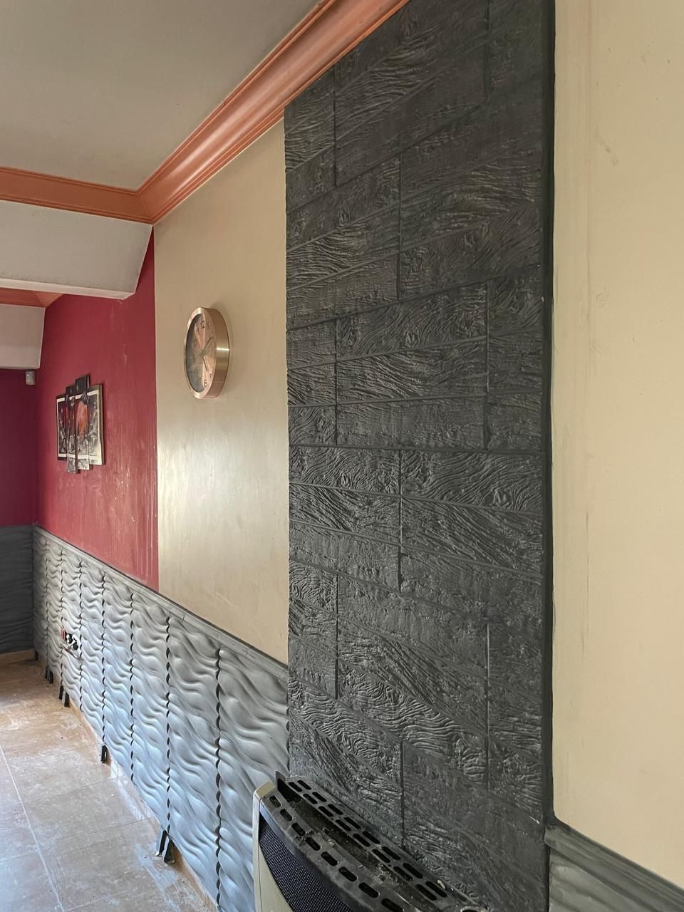 Pasillo con una sección de pared negra texturizada y paredes color crema. Techo con detalles en rosa y dorado.