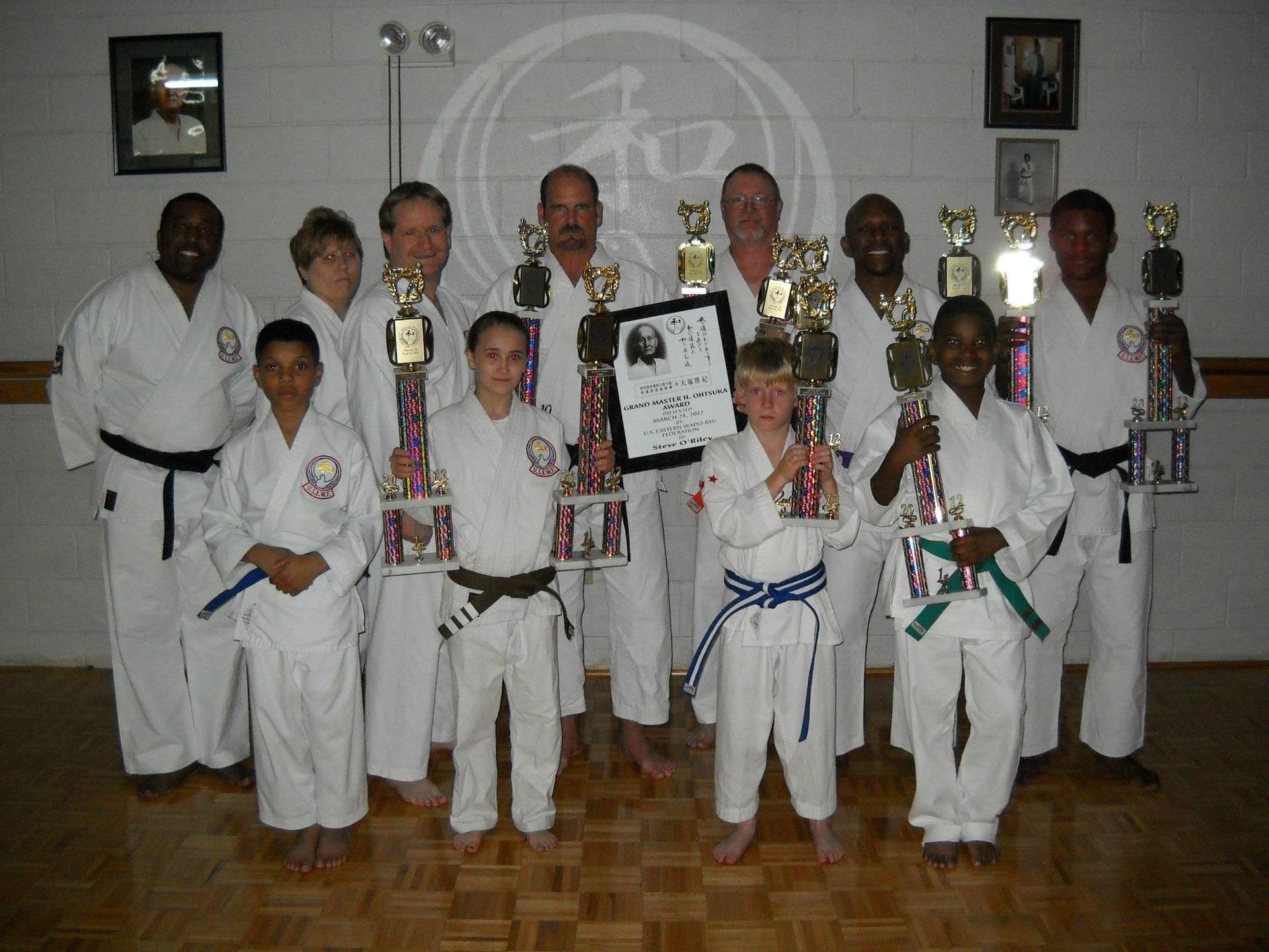 a group of people in karate uniforms holding trophies