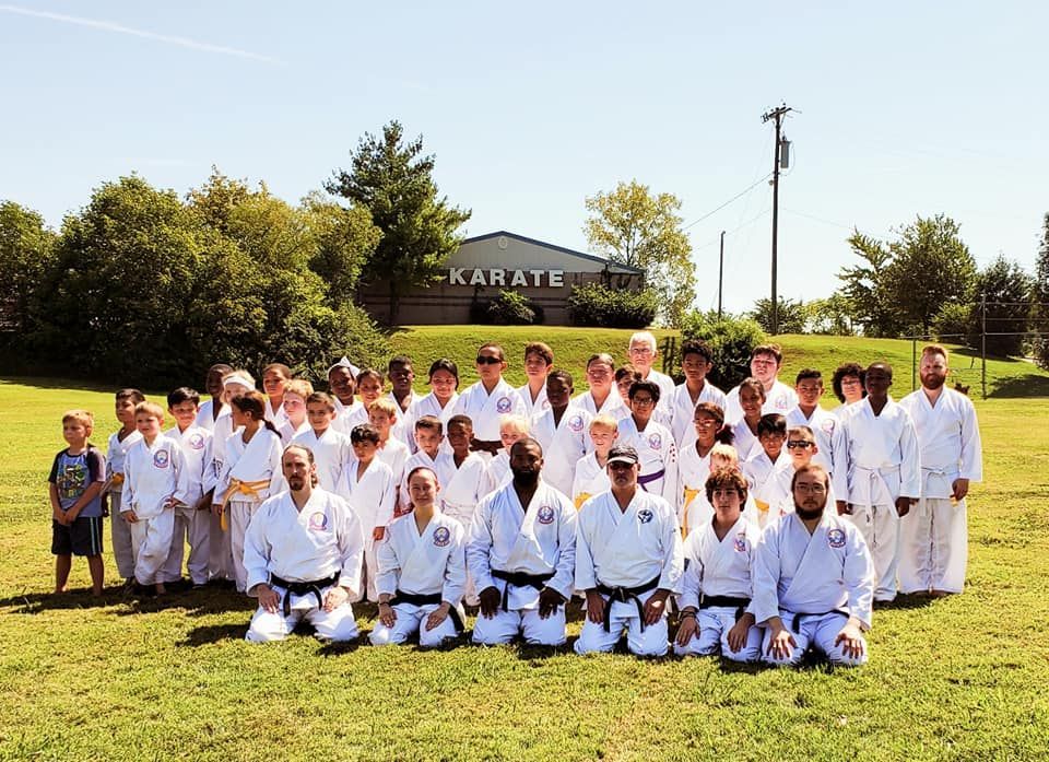 a group of people posing for a picture in front of the Karate building