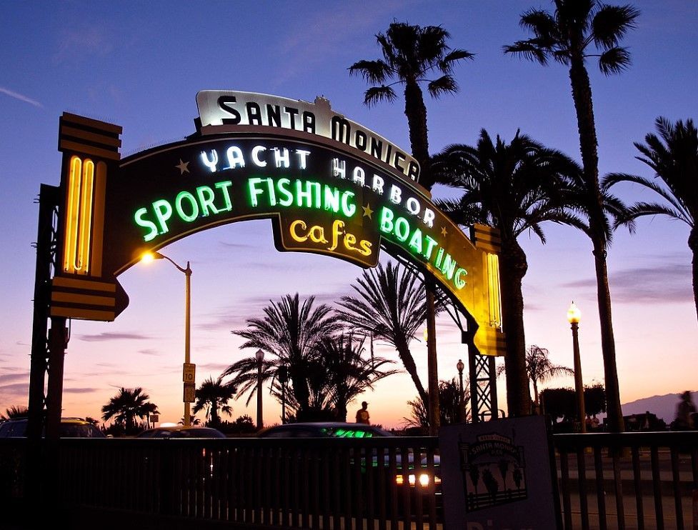 Santa Monica Yacht Harbor sign with palm trees at dusk.