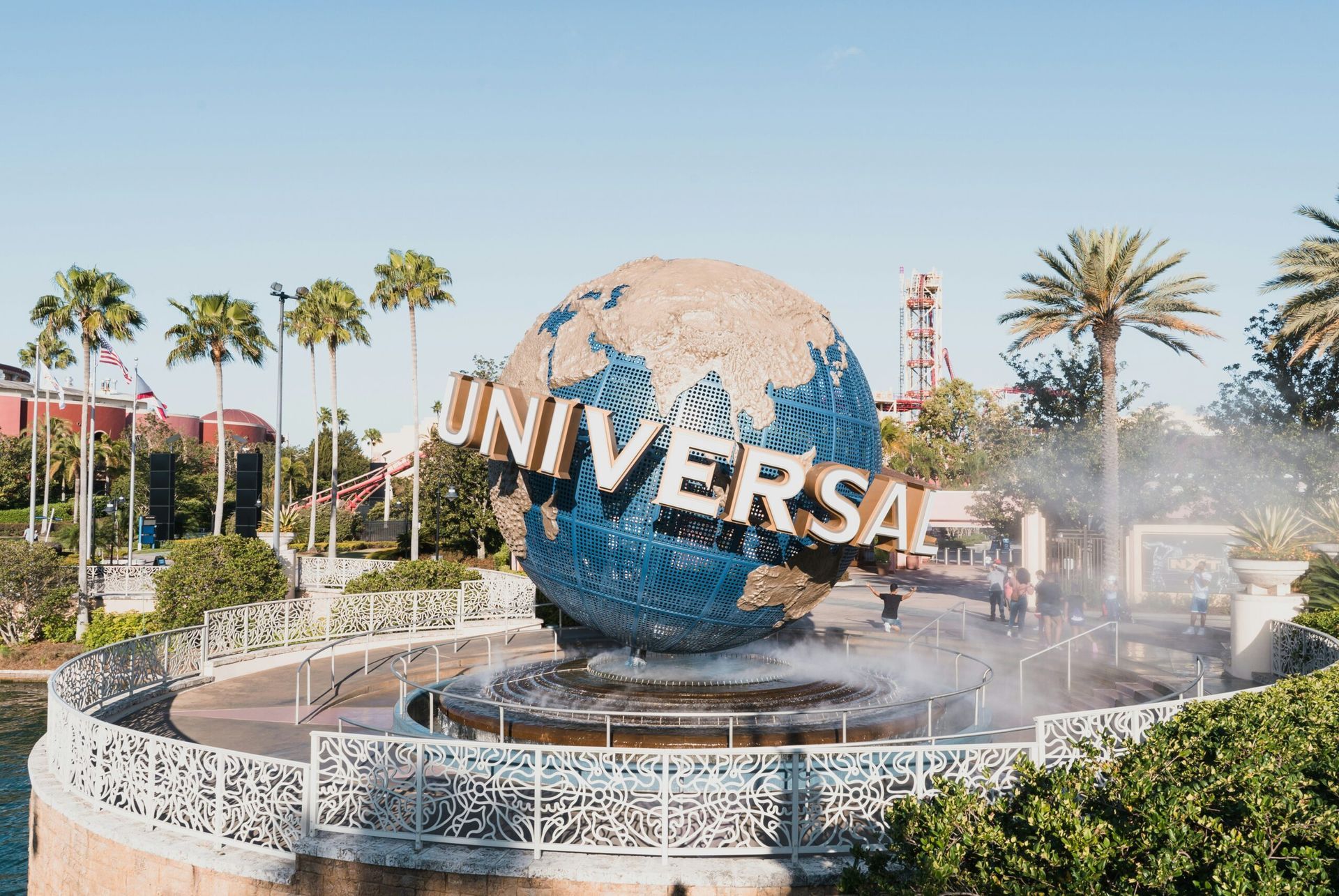 Universal globe sculpture with water fountain in front; blue, brown, and white. Sunny day.