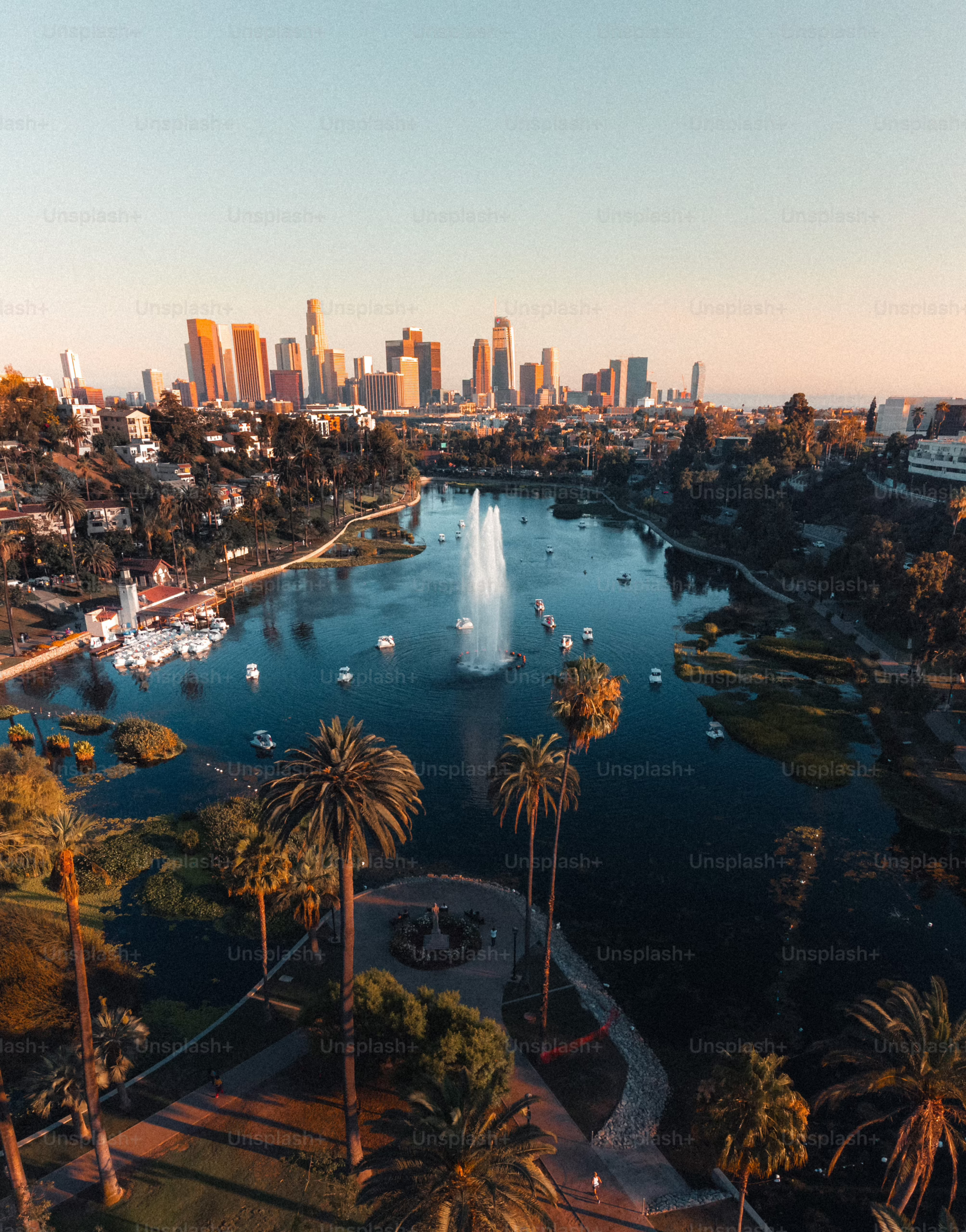 Aerial view of Echo Park Lake with a fountain, palm trees, and the Los Angeles skyline.