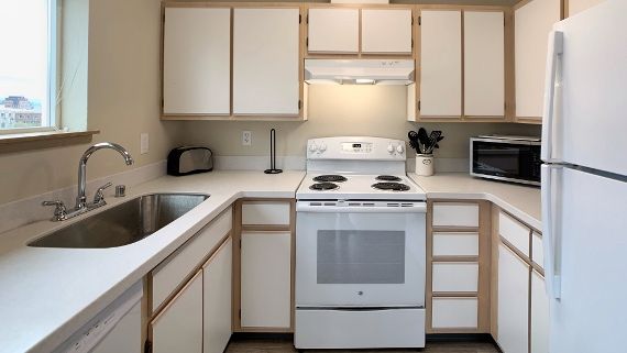 A kitchen with a stove , refrigerator , sink and microwave
