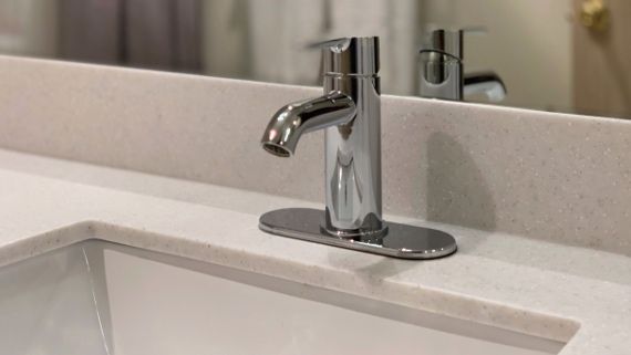 A bathroom sink with a chrome faucet and a mirror.