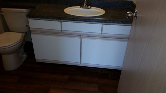 A bathroom with a toilet , sink and cabinets.