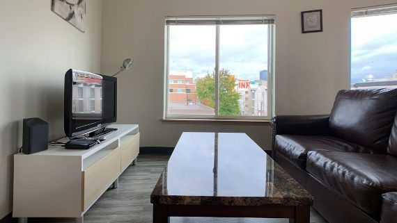 A living room with a couch , table , television and window.