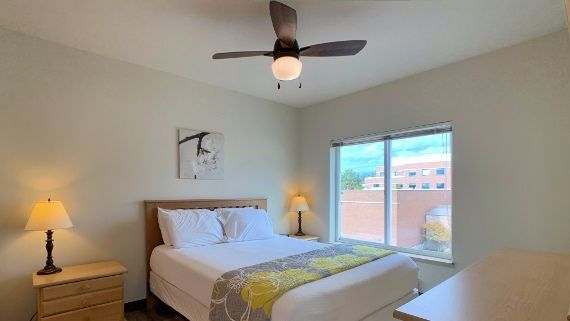 A bedroom with a king size bed and a ceiling fan.